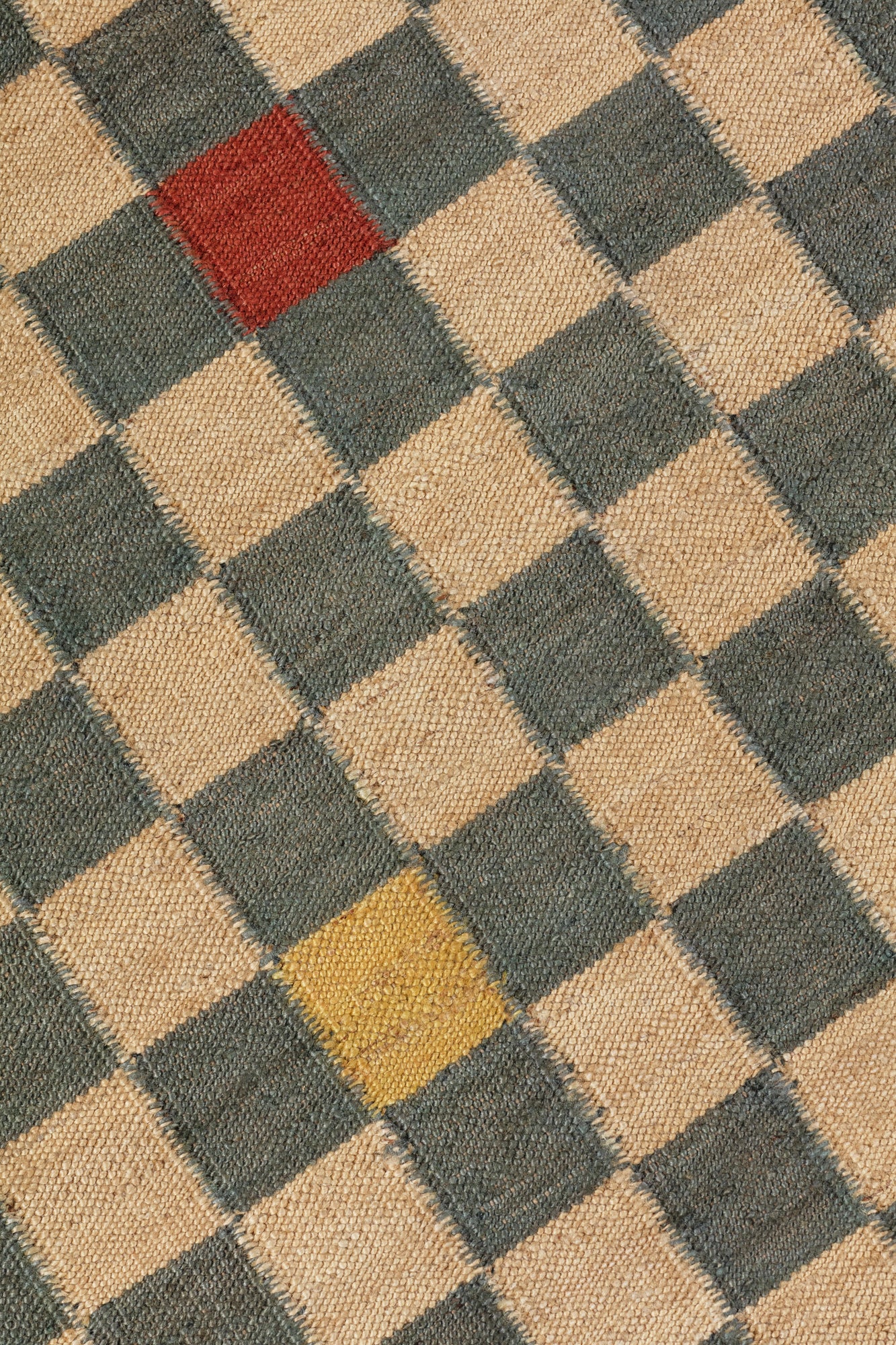 Detail of the Checkerboard Rug in bishop, a blue and white checkered pattern with random accents of red and yellow. 