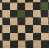 Detail of the Checkerboard Rug in King, a black and tan checkered pattern with random accents of green and white. 