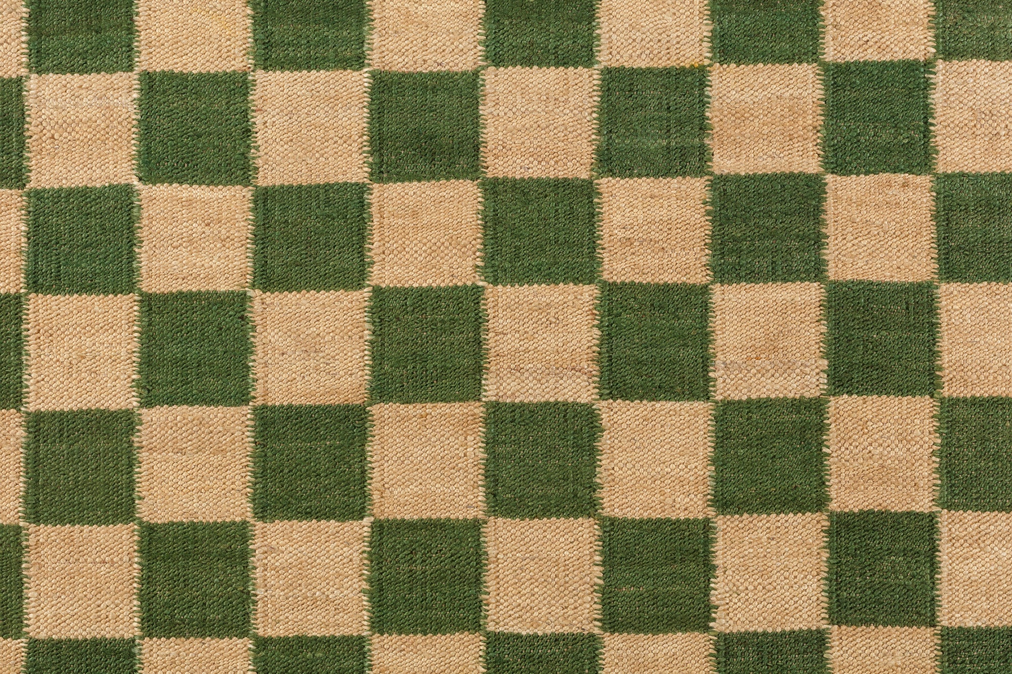 Detail of the Checkerboard Rug in Pawn, a green and tan checkered pattern. 