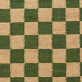 Detail of the Checkerboard Rug in Pawn, a green and tan checkered pattern. 