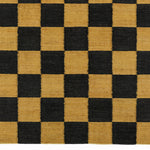 Detail of the Checkerboard Rug in Queen, a black and ochre yellow checkered pattern. 