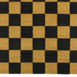 Detail of the Checkerboard Rug in Queen, a black and ochre yellow checkered pattern. 