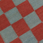 Detail of the Checkerboard Rug in Pawn, a red and sky blue checkered pattern. 