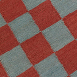 Detail of the Checkerboard Rug in Pawn, a red and sky blue checkered pattern. 
