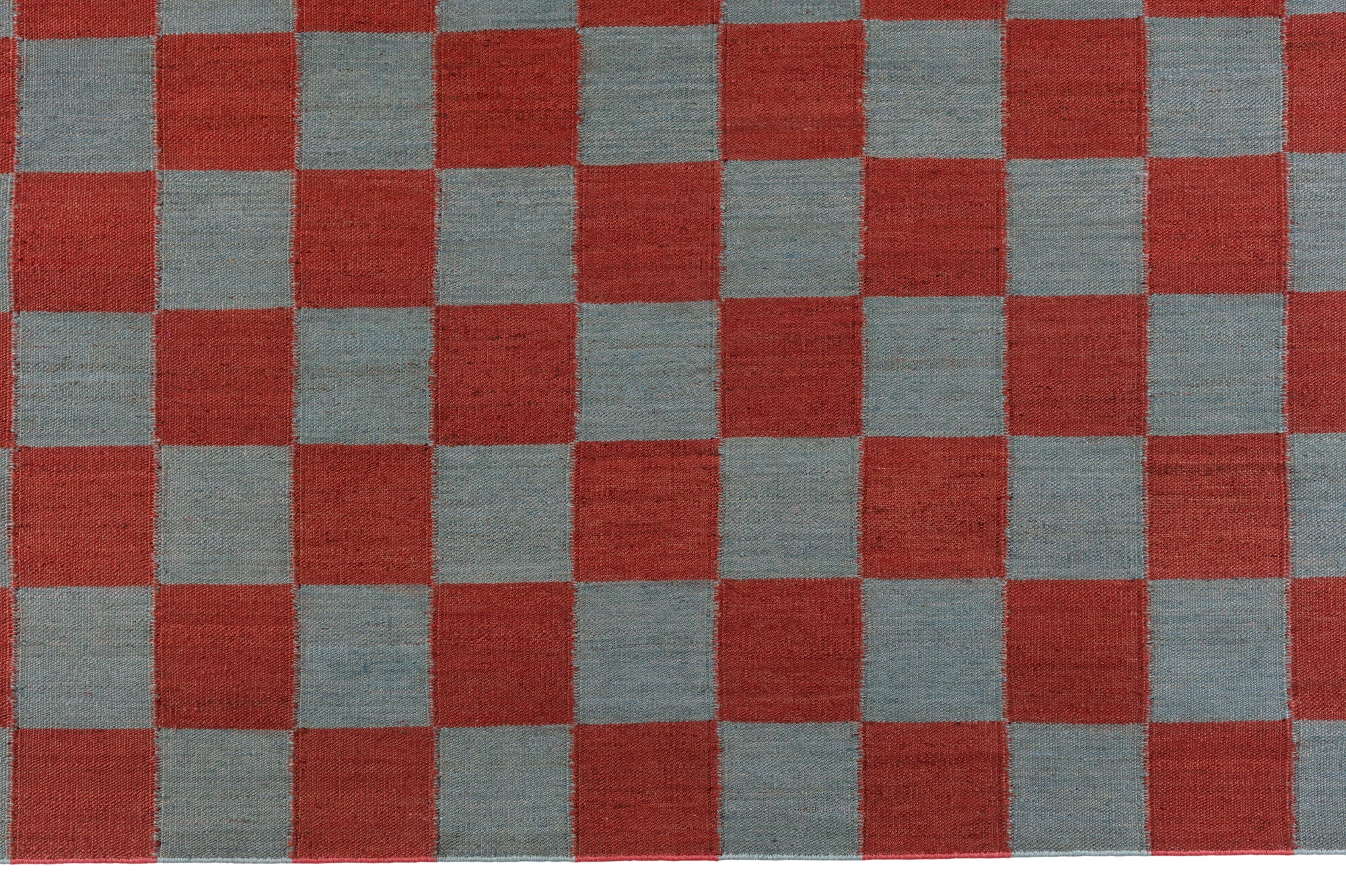 Detail of the Checkerboard Rug in Pawn, a red and sky blue checkered pattern. 