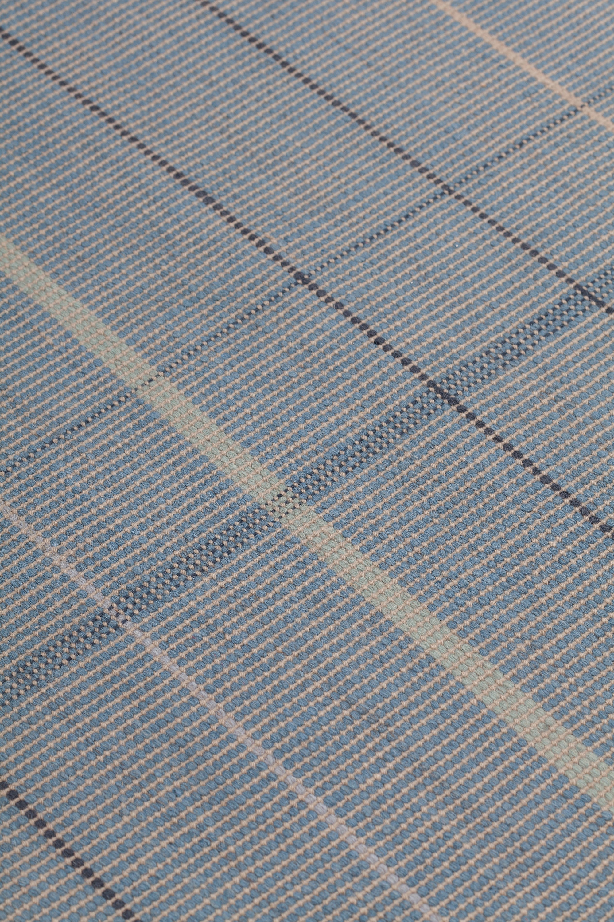 Detail of the Jasper Waffle Rug in Chalcedony, a large scale plaid pattern of denim blue, black, yellow and pale turqouise. 