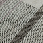 Detail of the Jasper Waffle Rug in Red Fossile, widely spaced stripes of yellow, pink, red, white and black on a split light grey fand ivory field. 