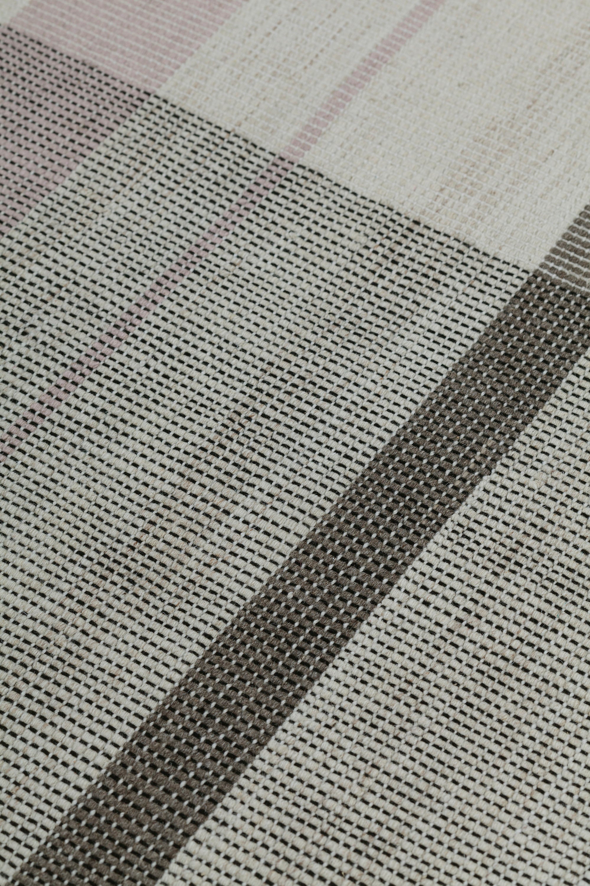 Detail of the Jasper Waffle Rug in Red Fossile, widely spaced stripes of yellow, pink, red, white and black on a split light grey fand ivory field. 