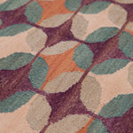Detail of the Petite Alhambra Rug featuring a pattern of linked circles that create a star like lattice in coral, taupe, turquoise and royal purple. 