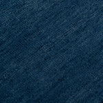Detail of the Plain Stitched Border Rug in Prussian Blue, a solid indigo rug with a black border with black border with blue and taupe dashes. 