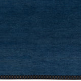 Detail of the Plain Stitched Border Rug in Prussian Blue, a solid indigo rug with a black border with black border with blue and taupe dashes. 
