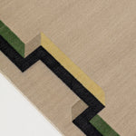 Detail of the Ponti Rug in Salvia, an ivory field with a geometric stair step border in black, with yellow, green and taupe. 