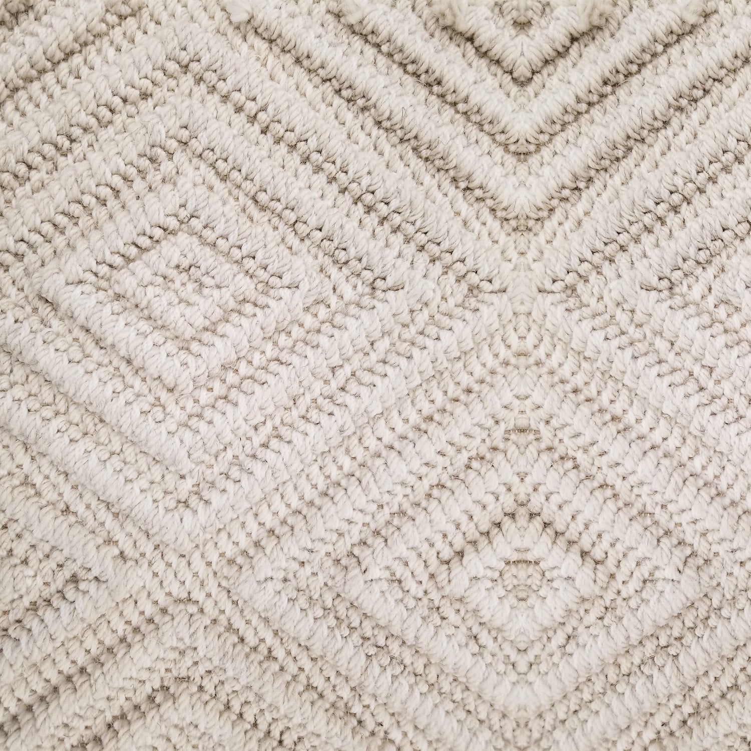 Wool broadloom carpet swatch woven in a dimensional diamond print in cream.