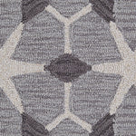 Detail of a wool broadloom carpet swatch in a geometric lattice pattern in cream and charcoal on a gray field.
