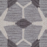 Detail of a wool broadloom carpet swatch in a geometric lattice pattern in cream and charcoal on a gray field.