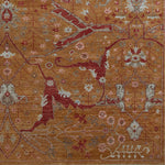 Woven rug swatch in a dense floral print in shades of red, pink and blue-gray on an orange field.