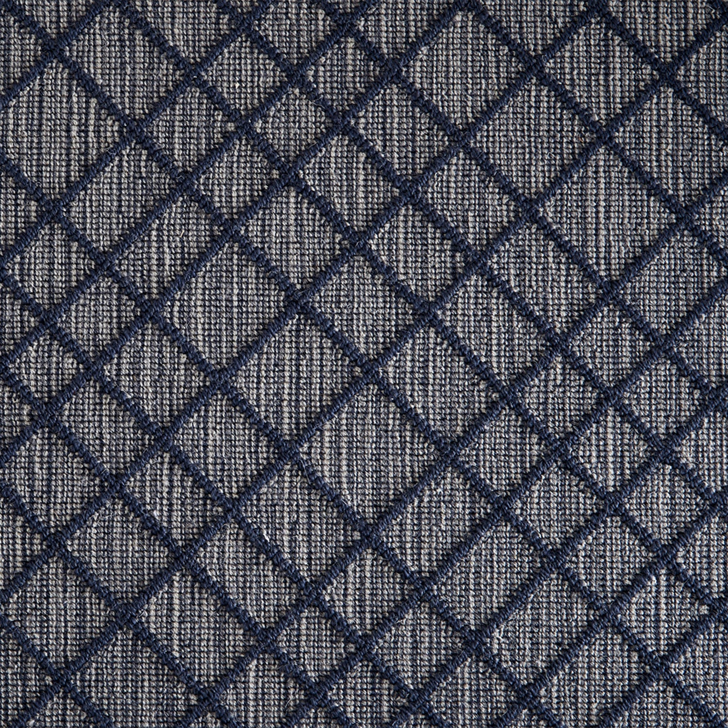 Wool-blend broadloom carpet swatch in a dimensional lattice print in navy on a mottled gray and cream field.