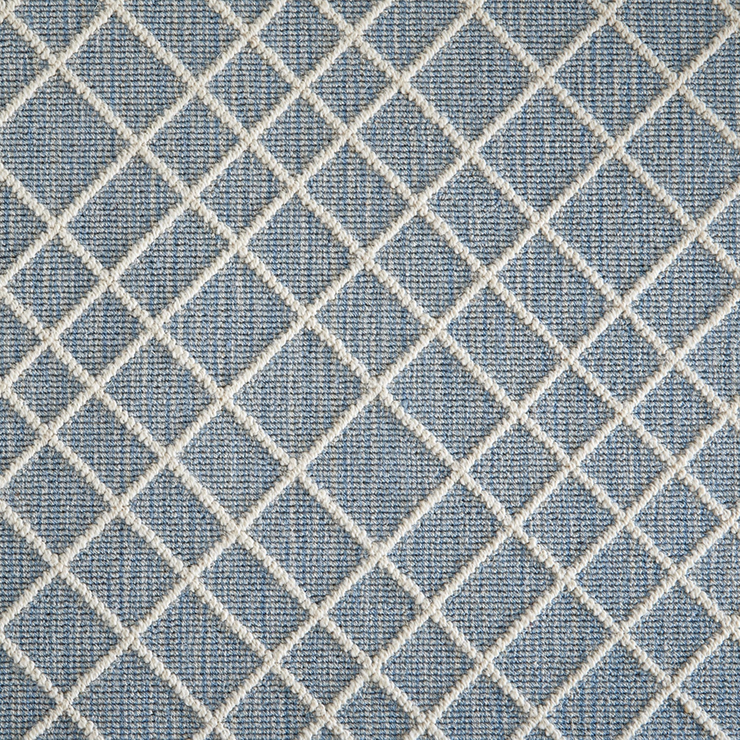 Wool-blend broadloom carpet swatch in a dimensional lattice print in cream on a mottled sky-blue field.