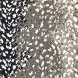 Wool broadloom carpet swatch in a white leopard print on an ombré background of black and gray.