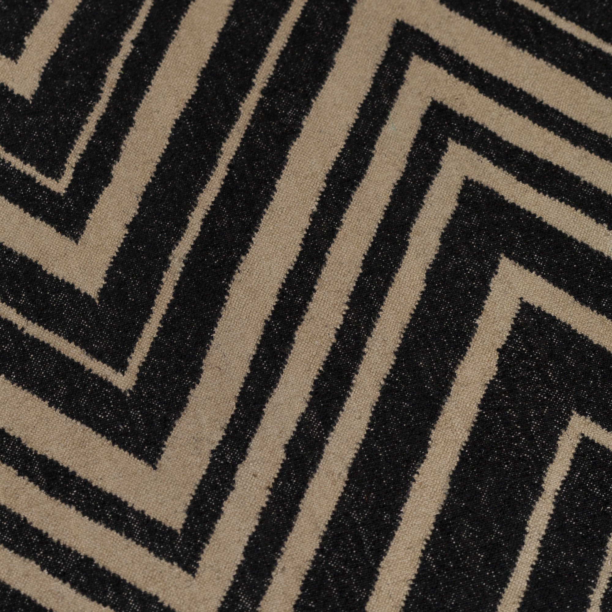 Detail of the Vertical Zig-Zag Rug in Onyx-Sandstone, a zig zag pattern in mixed widths in black and taupe.