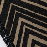 Detail of the Vertical Zig-Zag Rug in Onyx-Sandstone, a zig zag pattern in mixed widths in black and taupe with a fringed edge. 