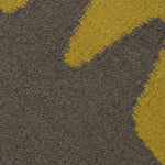 Detail of the Waver Rug in Cardinal Yellow, a dark taupe field with a yellow flame stitch border. 
