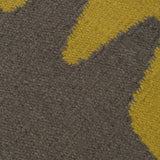 Detail of the Waver Rug in Cardinal Yellow, a dark taupe field with a yellow flame stitch border. 