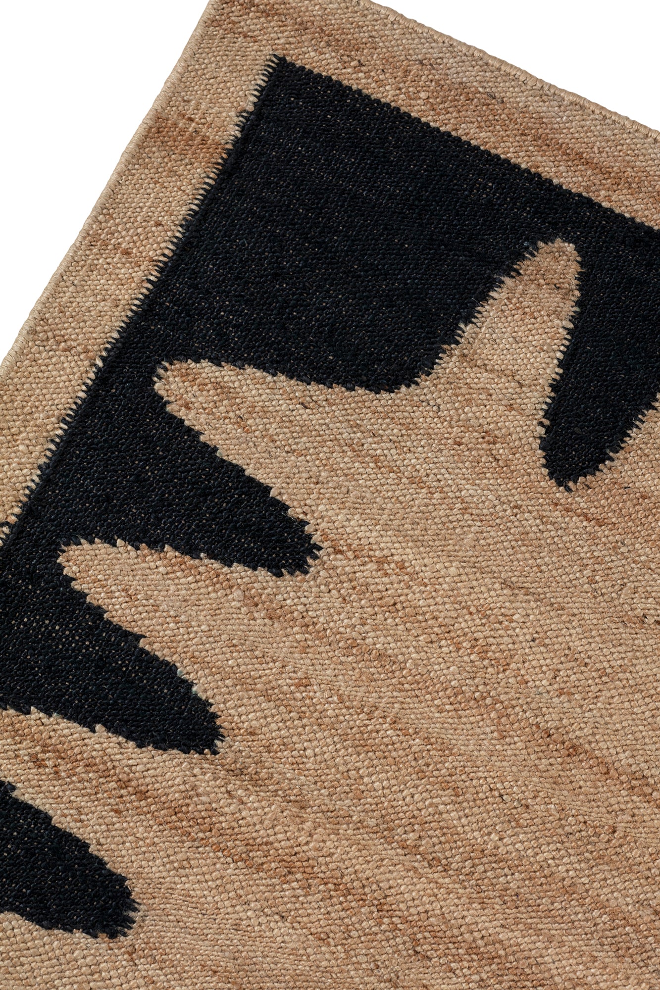 Detail of the Waver Rug in Jet Black, a strated ecru field with a black flame stitch border. 