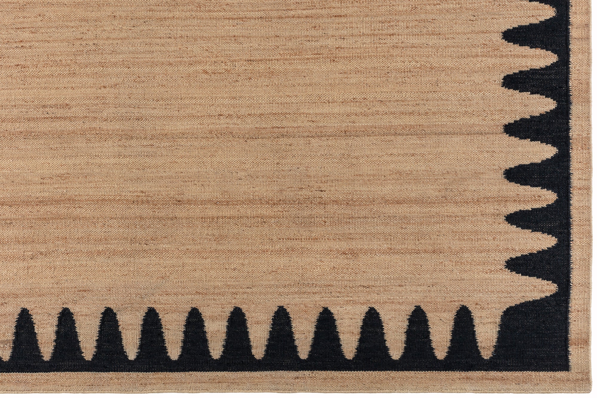 Detail of the Waver Rug in Jet Black, a strated ecru field with a black flame stitch border. 