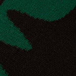Detail of the Waver Rug in Modernist Green, a solid black field with a green flame stitch border. 