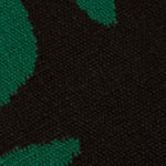 Detail of the Waver Rug in Modernist Green, a solid black field with a green flame stitch border. 