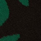 Detail of the Waver Rug in Modernist Green, a solid black field with a green flame stitch border. 