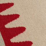 Detail of the Waver Rug in Pillbox Red, a solid Ivory field with a red flame stitch border. 