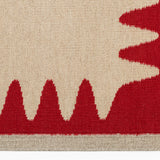 Detail of the Waver Rug in Pillbox Red, a solid Ivory field with a red flame stitch border. 