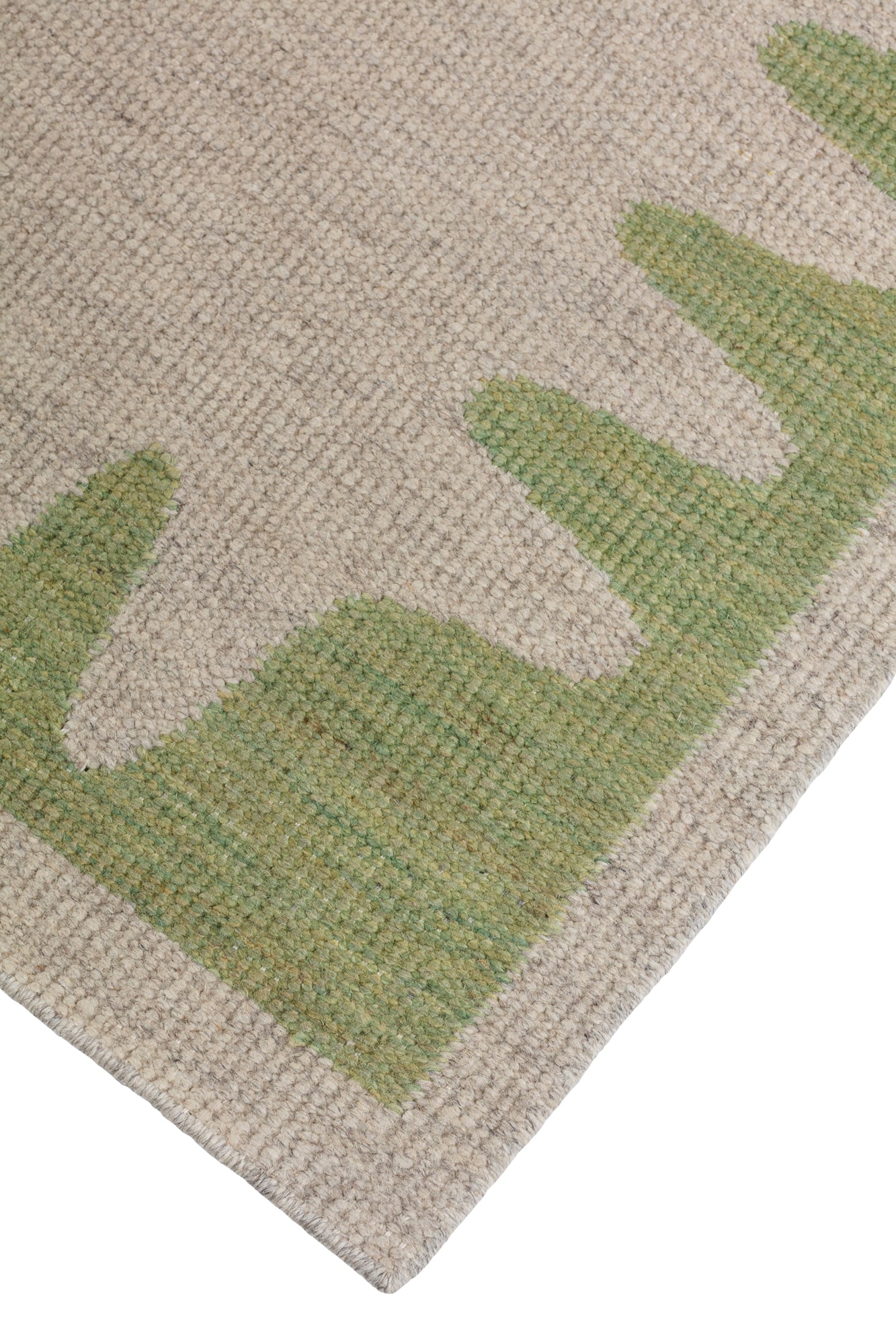 Detail of the Waver Rug in Sage, a strated taupe field with a sage green flame stitch border. 