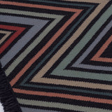 Detail of the To The Point Rug in Hessonite-Garnet-Slate, a zig zag pattern in red, blue coral with black, with a black fringed edge. 