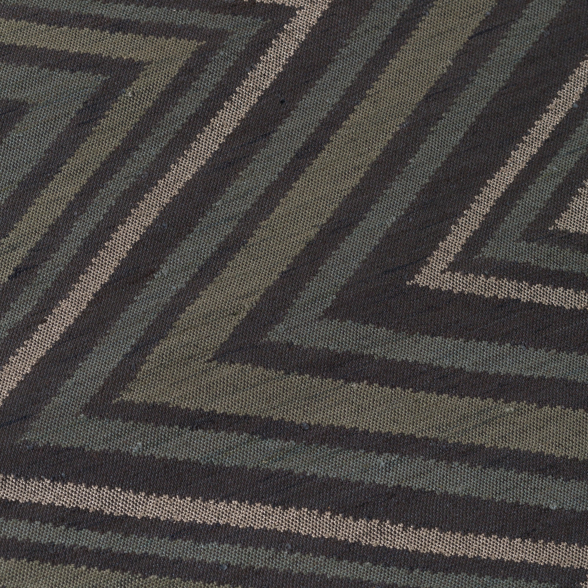 Detail of To The Point Rug in Pyrite-Metallic, a zig zag pattern in dark greens, metallic ecru and black.