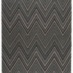 Full size To The Point Rug in Pyrite-Metallic, a zig zag pattern in dark greens, metallic ecru and black, with a mulit color tasseled edge. 