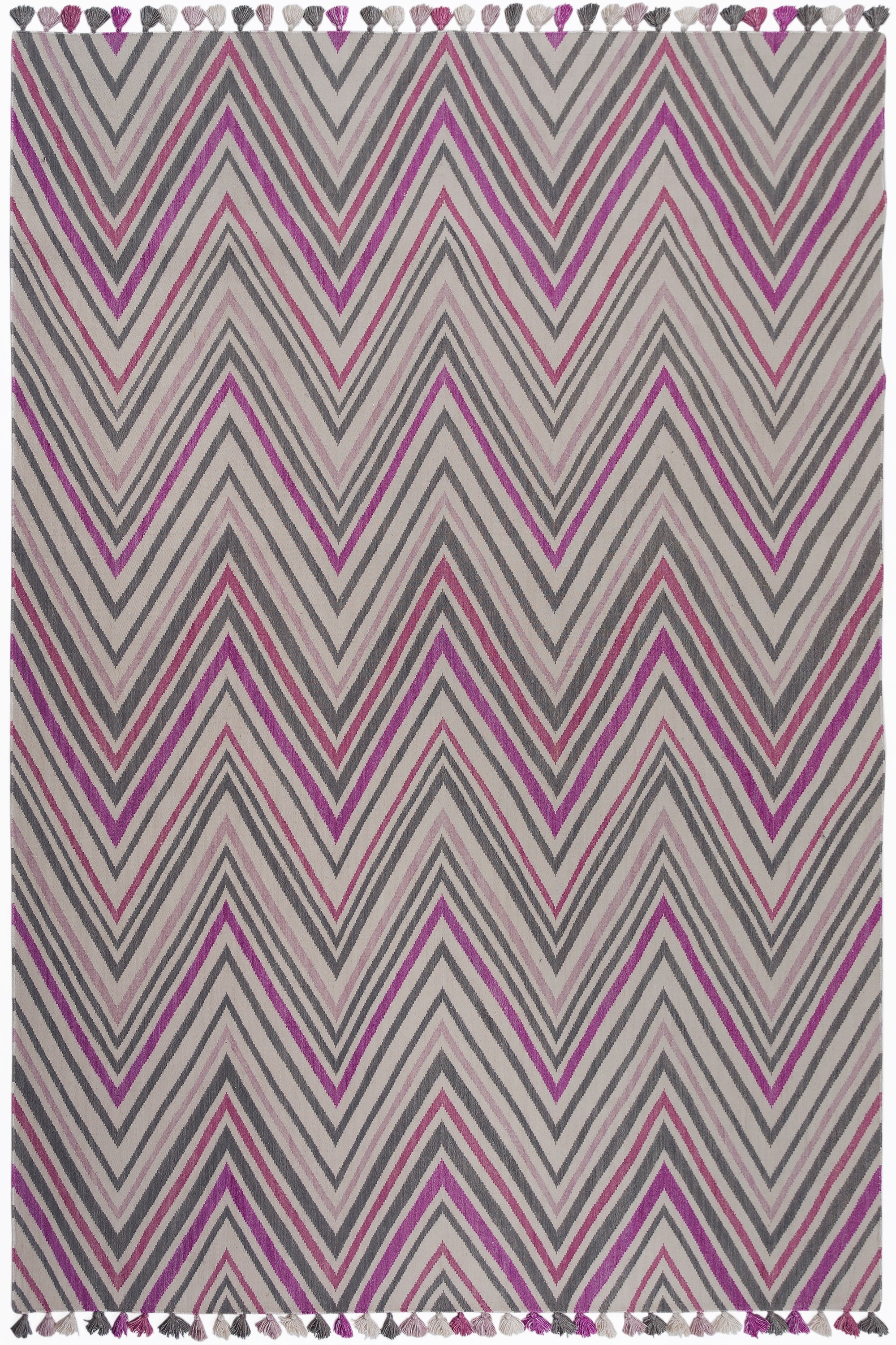 Zig Zag Rug in Ruby-Rose, a mutli color zig zag pattern in fucshia, magenta, link and charcoal on a white field with a tassled edge. 