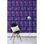 A chair and floor lamp in front of a wall papered in a large-scale pattern of abstract purple watercolor shapes on a dark purple background.