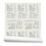 Partially unrolled wallpaper in a large-scale pattern of abstract gray watercolor shapes on a cream background.