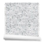 Partially unrolled wallpaper in a dense hand-drawn geometric motif in shades of gray on a white background.
