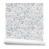 Partially unrolled wallpaper in a dense hand-drawn geometric motif in shades of gray on a white background.
