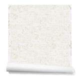 Partially unrolled wallpaper in a dense hand-drawn geometric motif in shades of tan on a white background.