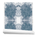 Partially unrolled wallpaper in a dense hand-drawn symmetrical pattern in shades of blue on a white background.