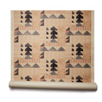 Partially unrolled wallpaper roll with layered geometric shapes in shades of black, beige and rust printed on a tan background.